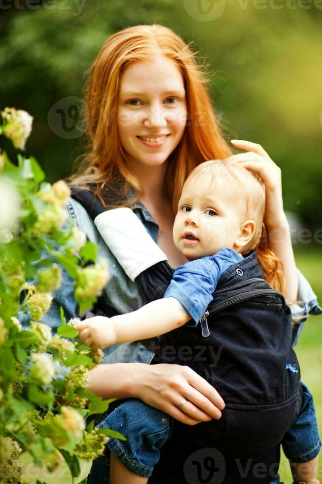 ein Frau halten ein Baby im ein Träger foto