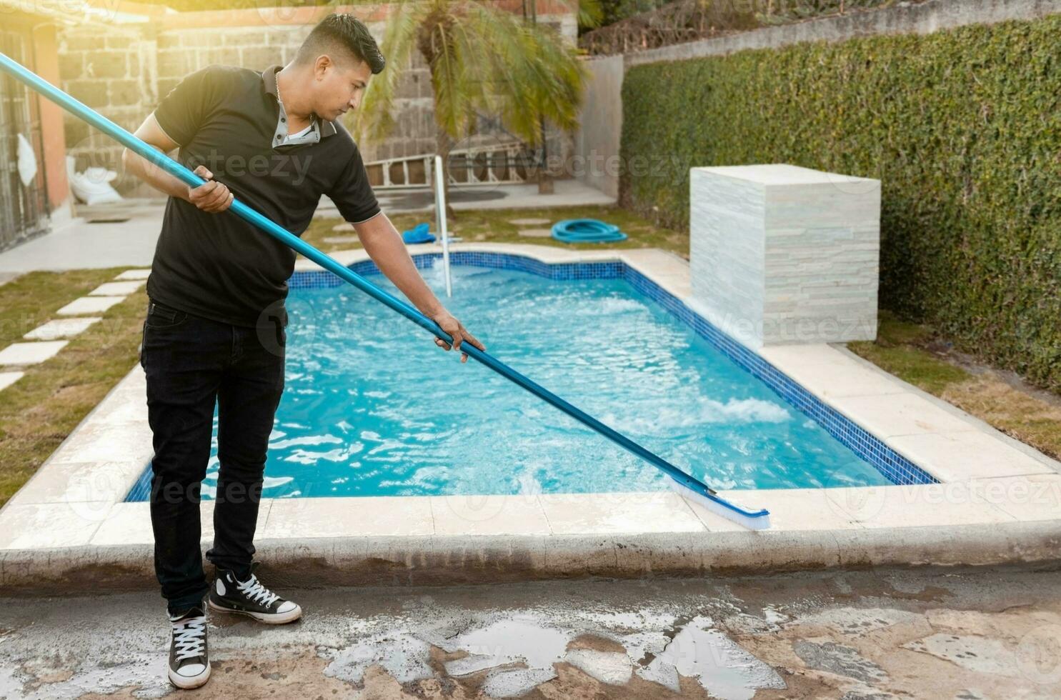 Schwimmen Schwimmbad Reinigung mit Bürste. Instandhaltung Person Reinigung Schwimmen Schwimmbad mit Bürste, Arbeiter Reinigung ein Schwimmen Schwimmbad mit Besondere Bürste foto