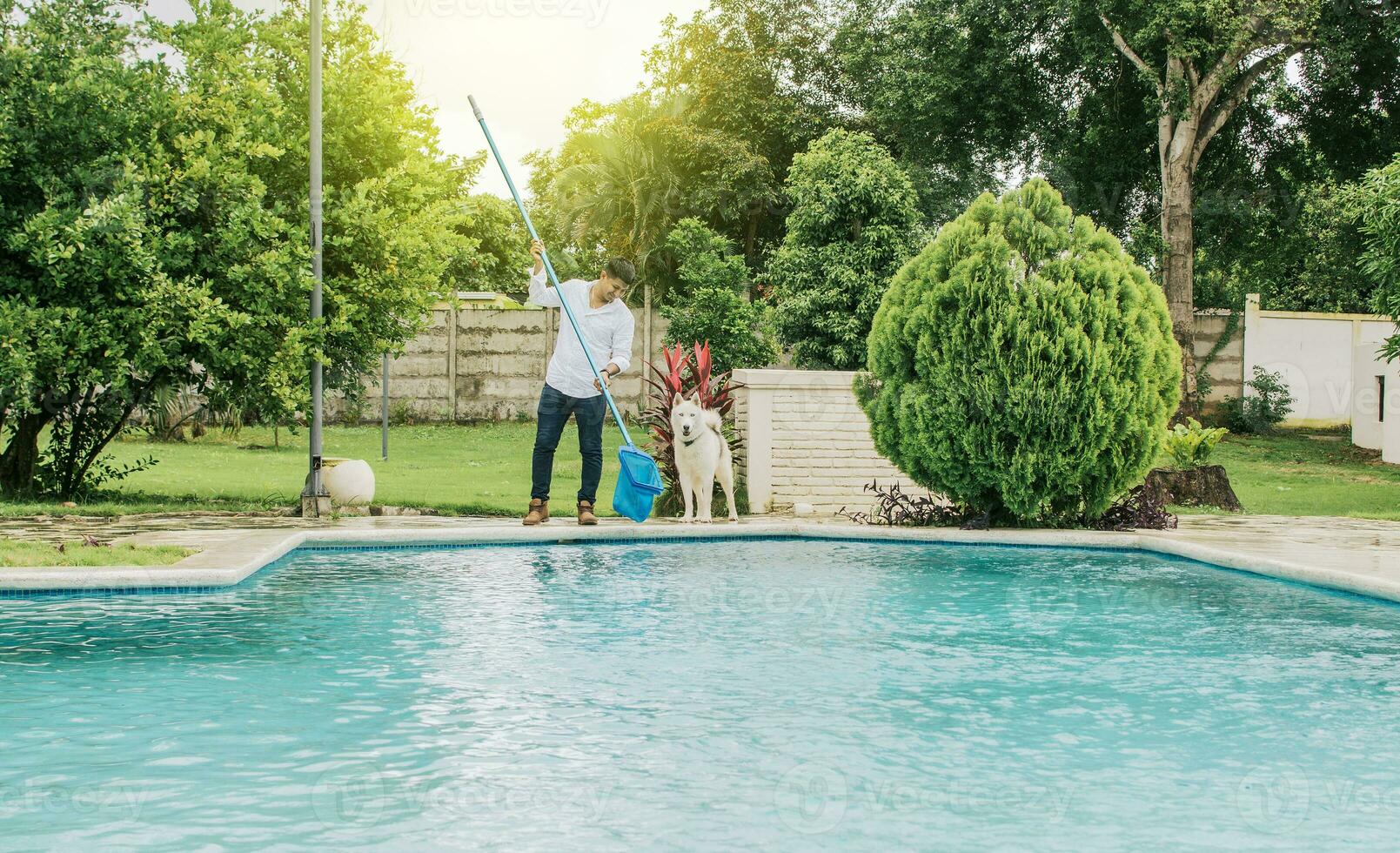 Mann Reinigung ein Schwimmen Schwimmbad mit Abschäumer, Instandhaltung Person Reinigung ein Schwimmen Schwimmbad mit Blatt Pflücker, Schwimmen Schwimmbad Reinigung und Instandhaltung Konzept foto