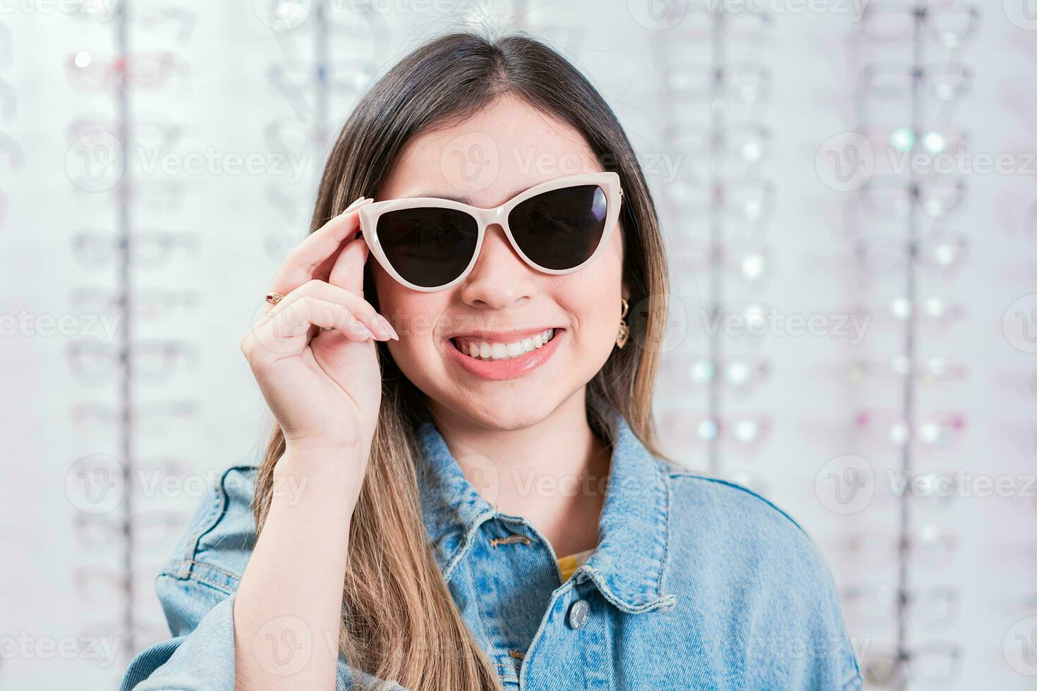 schön Mädchen versuchen auf Brille im ein Auge speichern. lächelnd weiblich Kunde versuchen auf Brille im Auge Geschäft foto