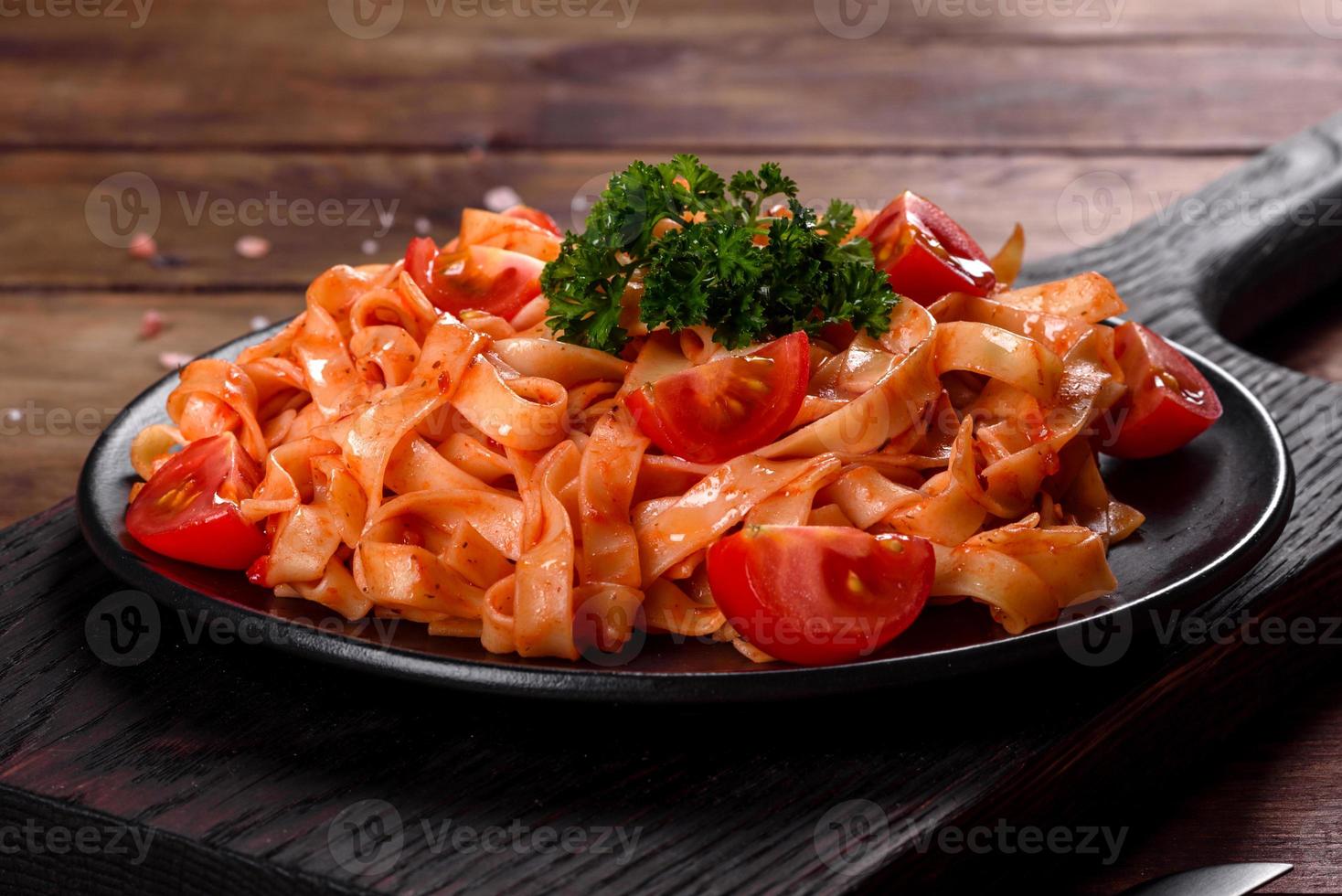 köstliche frische Paste mit Tomatensauce mit Gewürzen und Kräutern auf dunklem Hintergrund foto