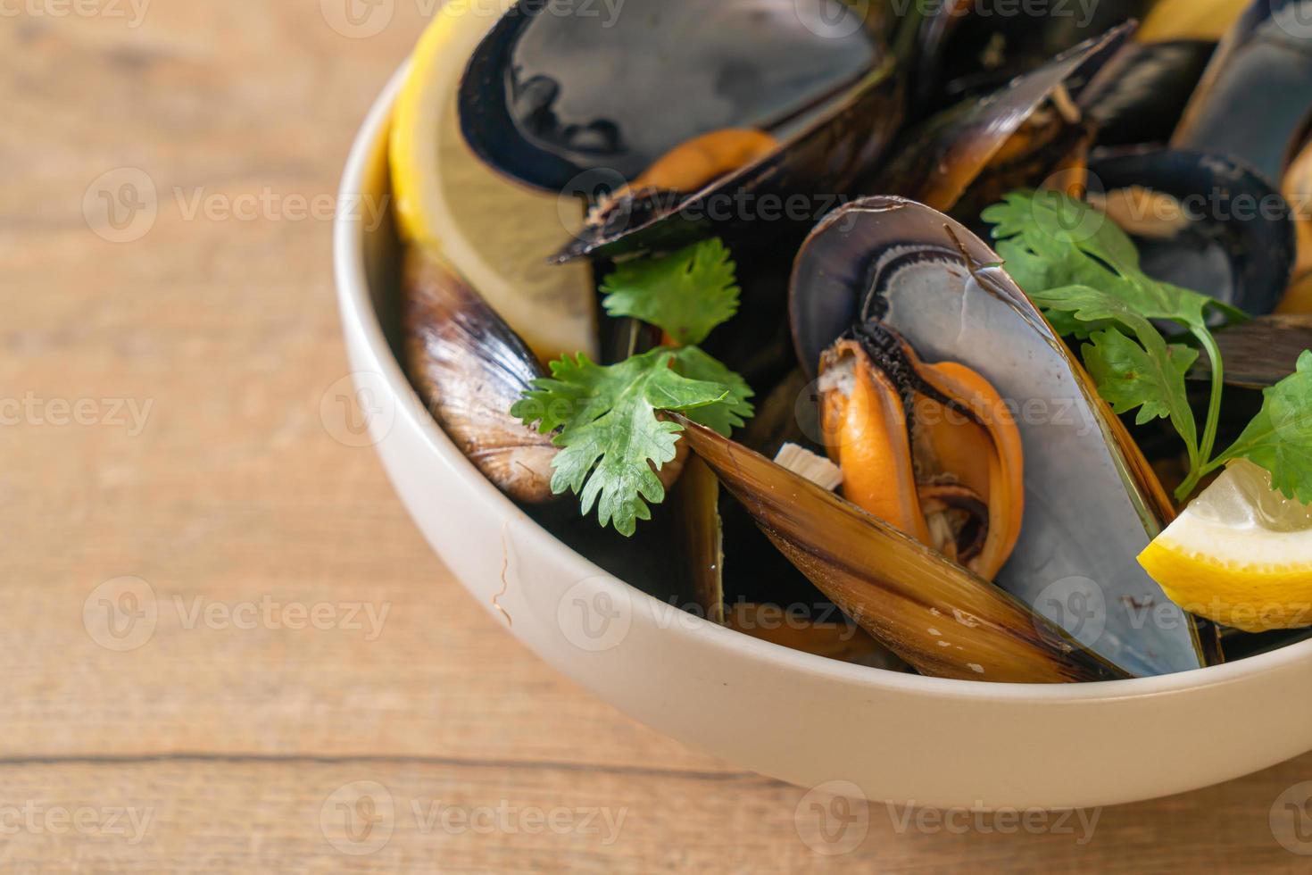 Muscheln mit Kräutern in einer Schüssel mit Zitrone foto