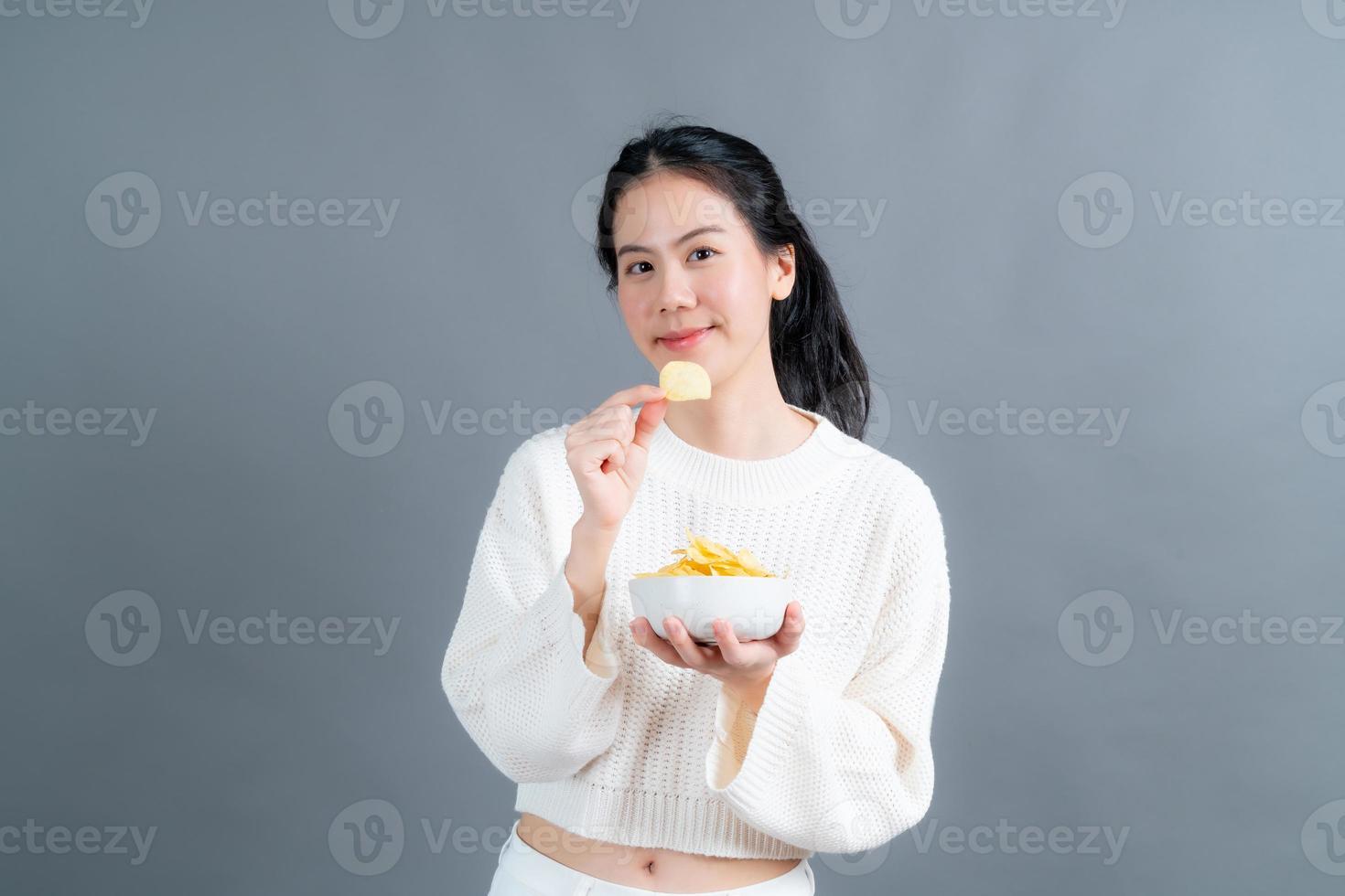 junge asiatische frau isst kartoffelchips foto