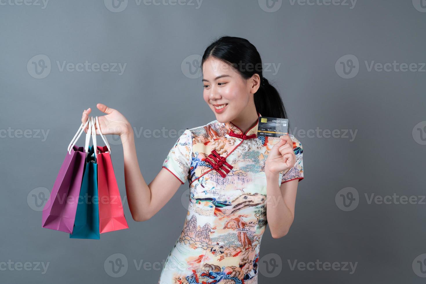 asiatische frau trägt chinesisches traditionelles kleid mit einkaufstasche und kreditkarte foto