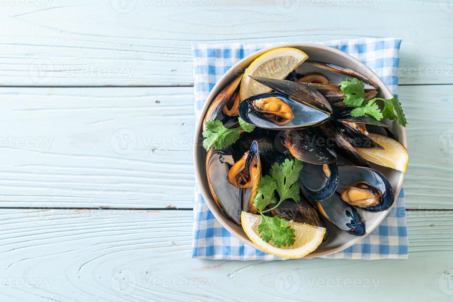 Muscheln mit Kräutern in einer Schüssel mit Zitrone foto