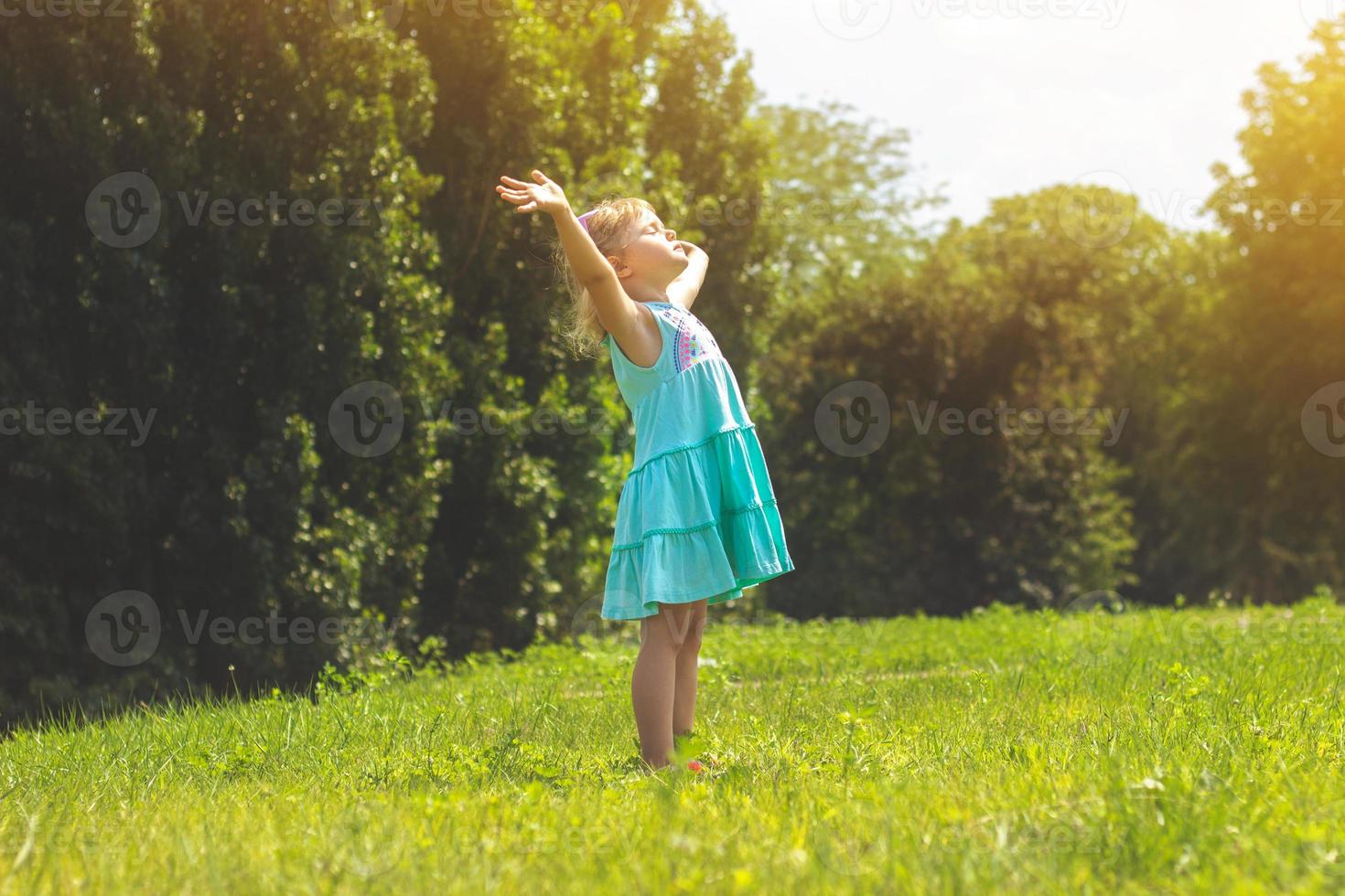 kleines Mädchen im Park mit ihren Armen offenes Lebenskonzept foto