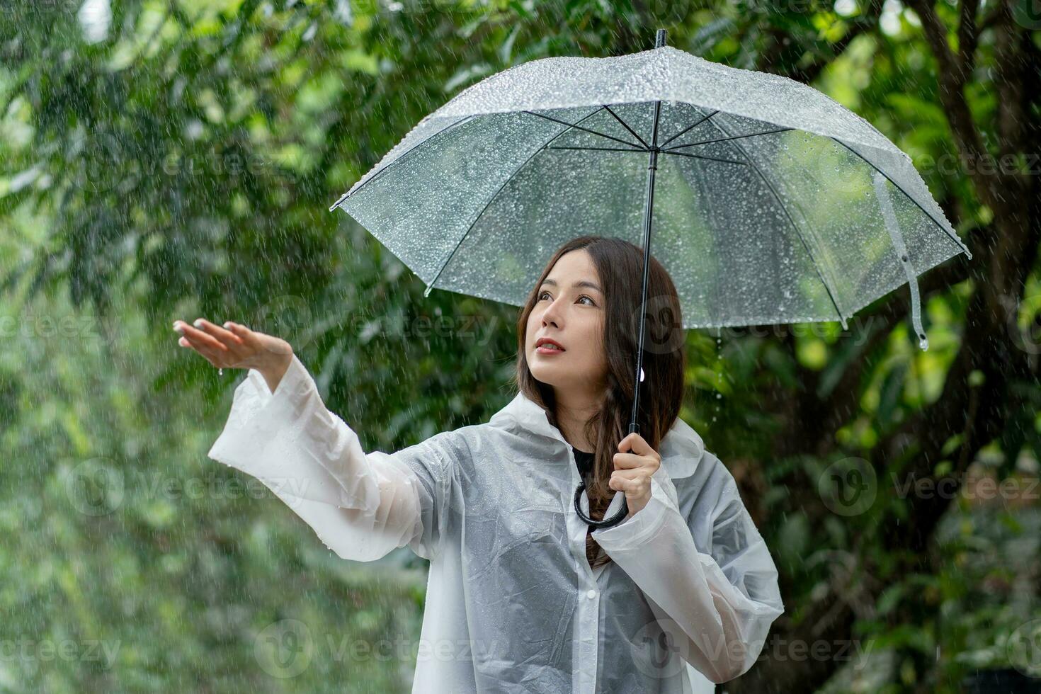 asiatisch schön Frau halten Regenschirm im regnet Jahreszeit foto