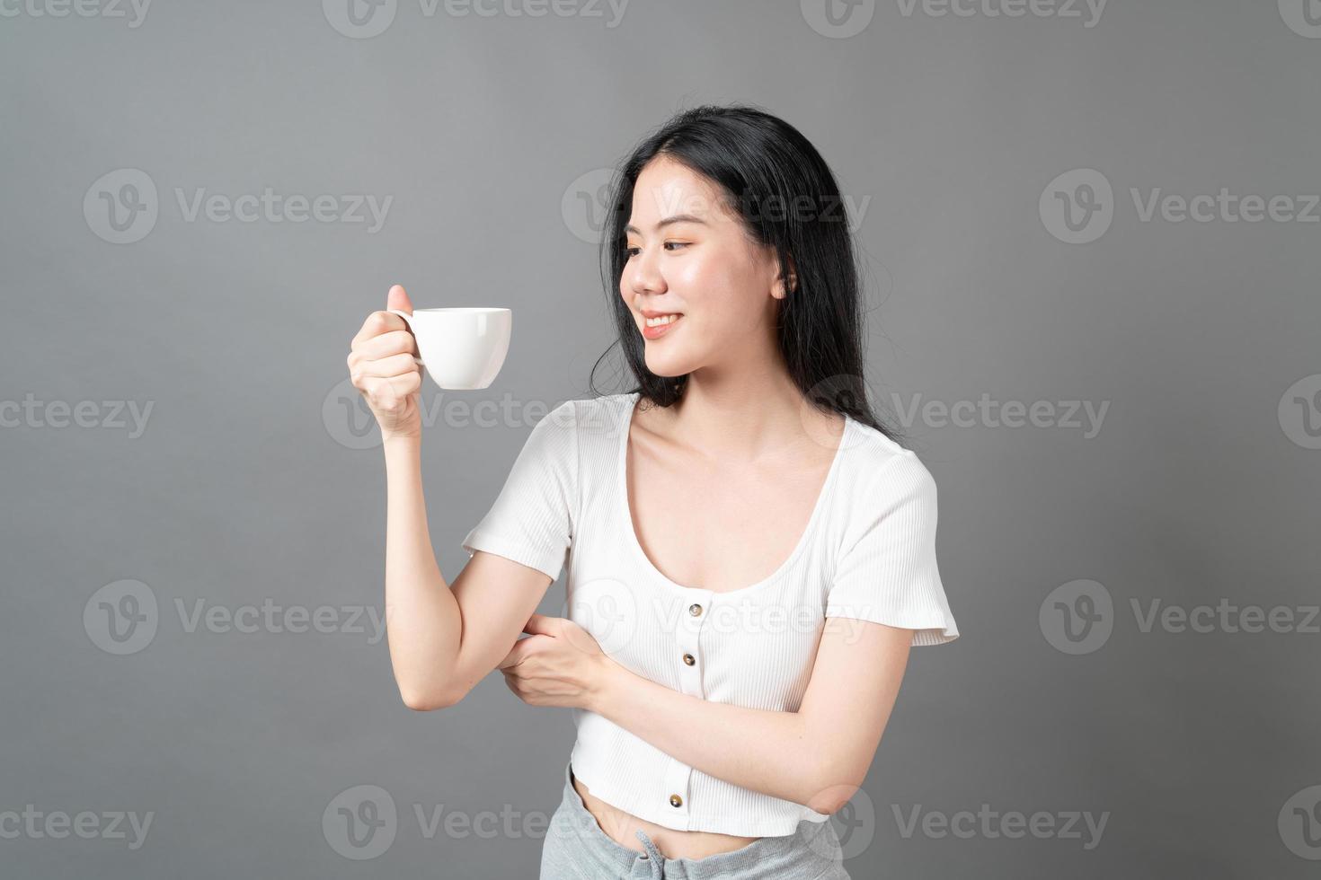 junge asiatische frau mit glücklichem gesicht und hand, die kaffeetasse hält foto