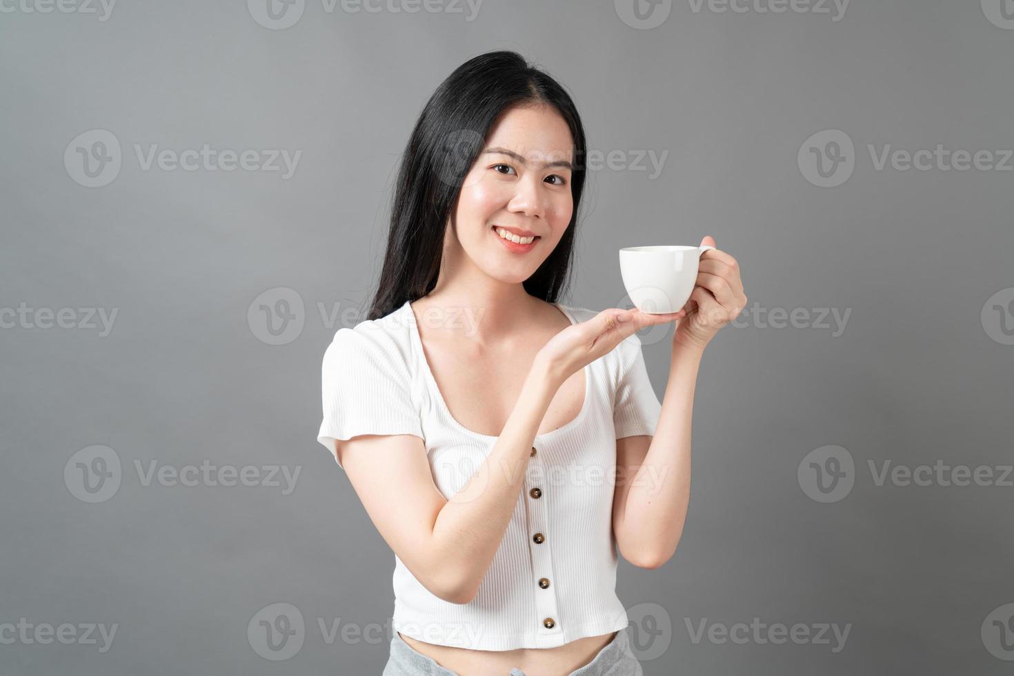junge asiatische frau mit glücklichem gesicht und hand, die kaffeetasse hält foto