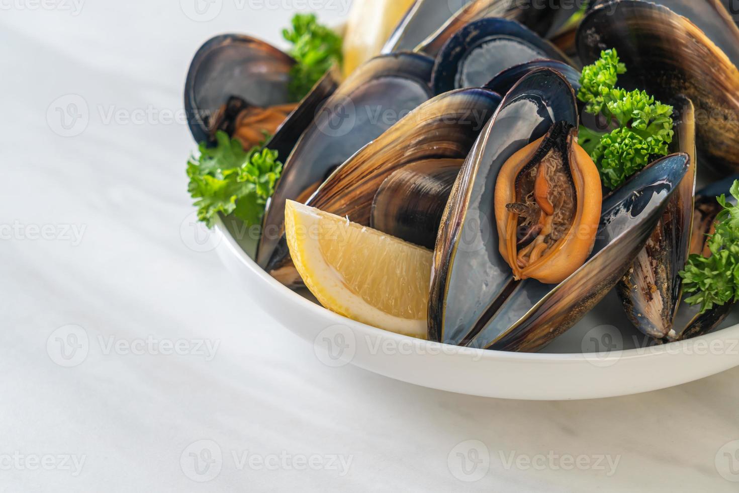 Muscheln mit Kräutern in einer Schüssel mit Zitrone foto