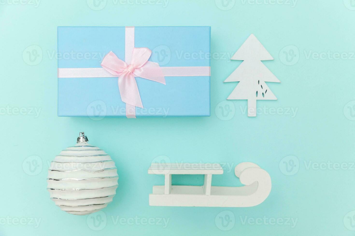 einfach minimal Komposition Winter Objekte Ornament Schlitten Tanne Baum Ball Geschenk Box isoliert auf Blau Pastell- modisch Hintergrund foto