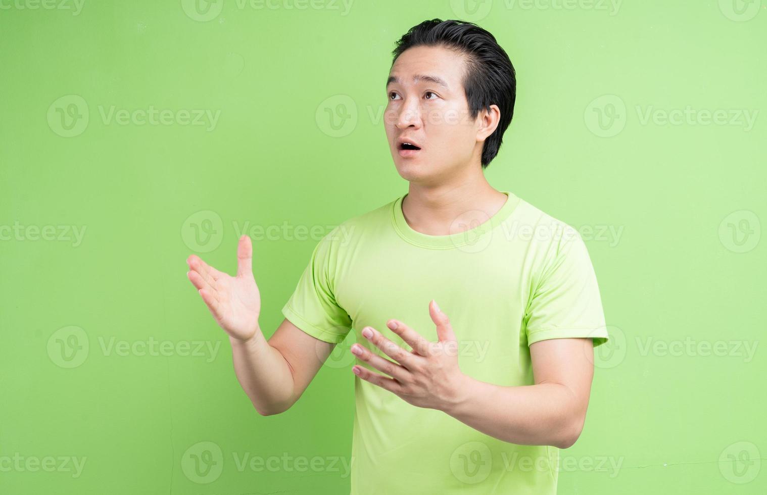 Porträt des asiatischen Mannes im grünen T-Shirt posiert auf grünem Hintergrund foto