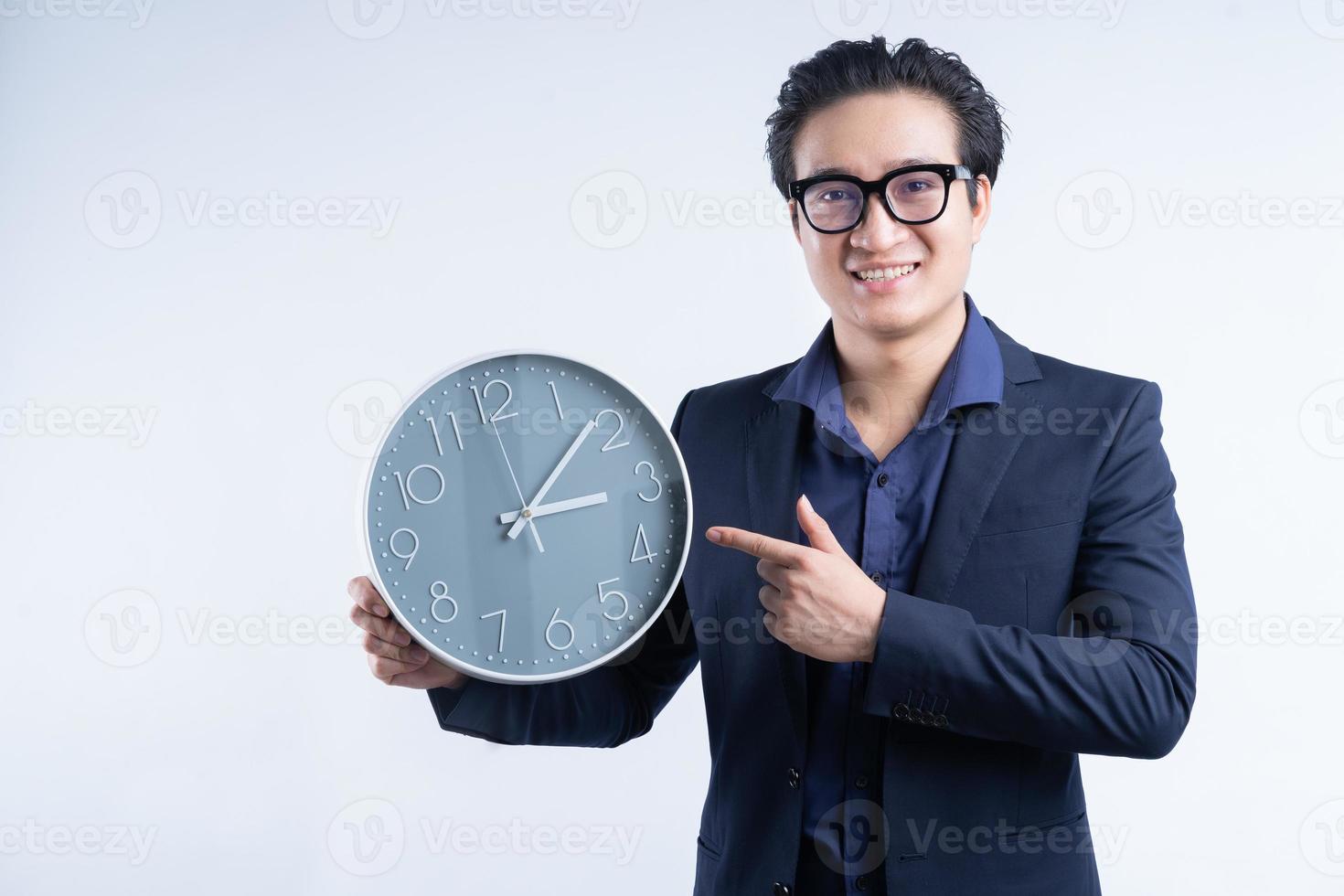 Porträt des asiatischen Geschäftsmannes, der Uhr hält foto