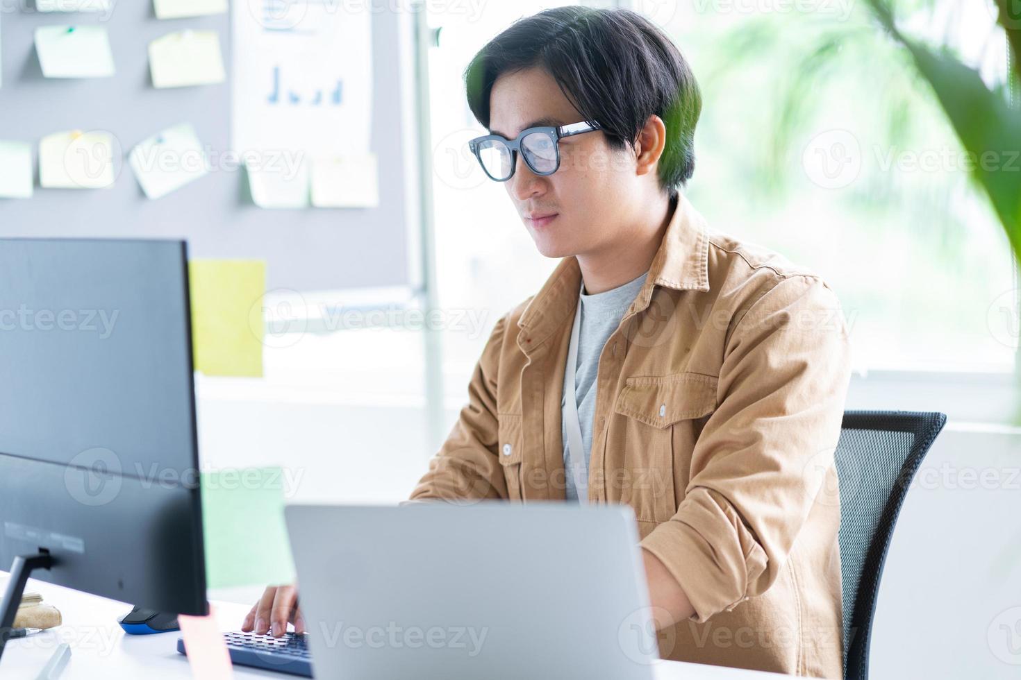 asiatischer Geschäftsmann, der mit Laptop im Büro arbeitet foto