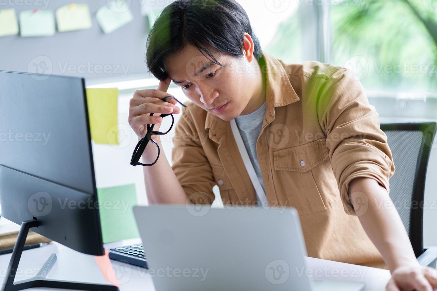 asiatischer Geschäftsmann, der mit Computer im Büro arbeitet foto