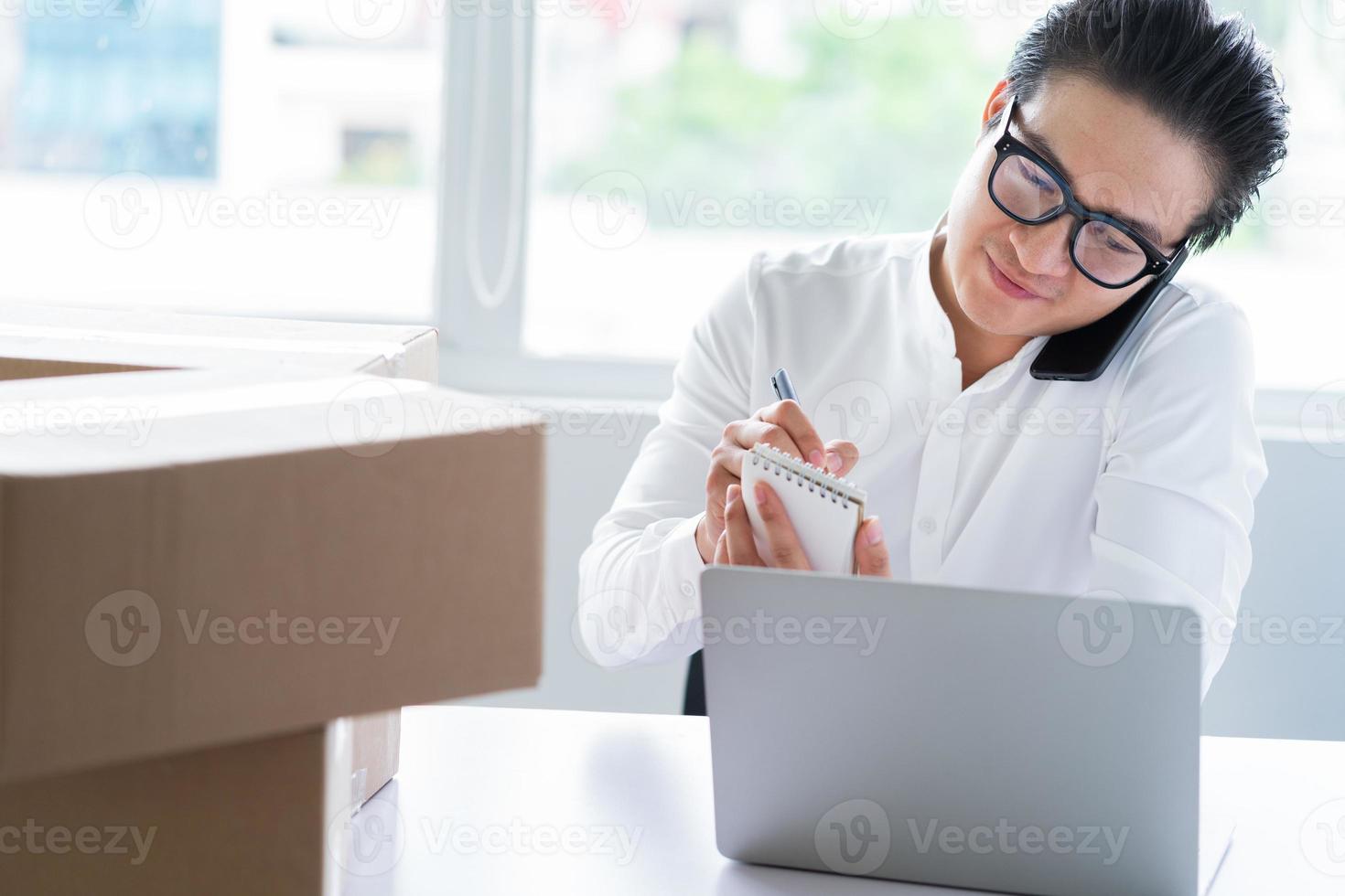 asiatischer Geschäftsmann, der Waren verpackt, um an Kunden zu senden foto