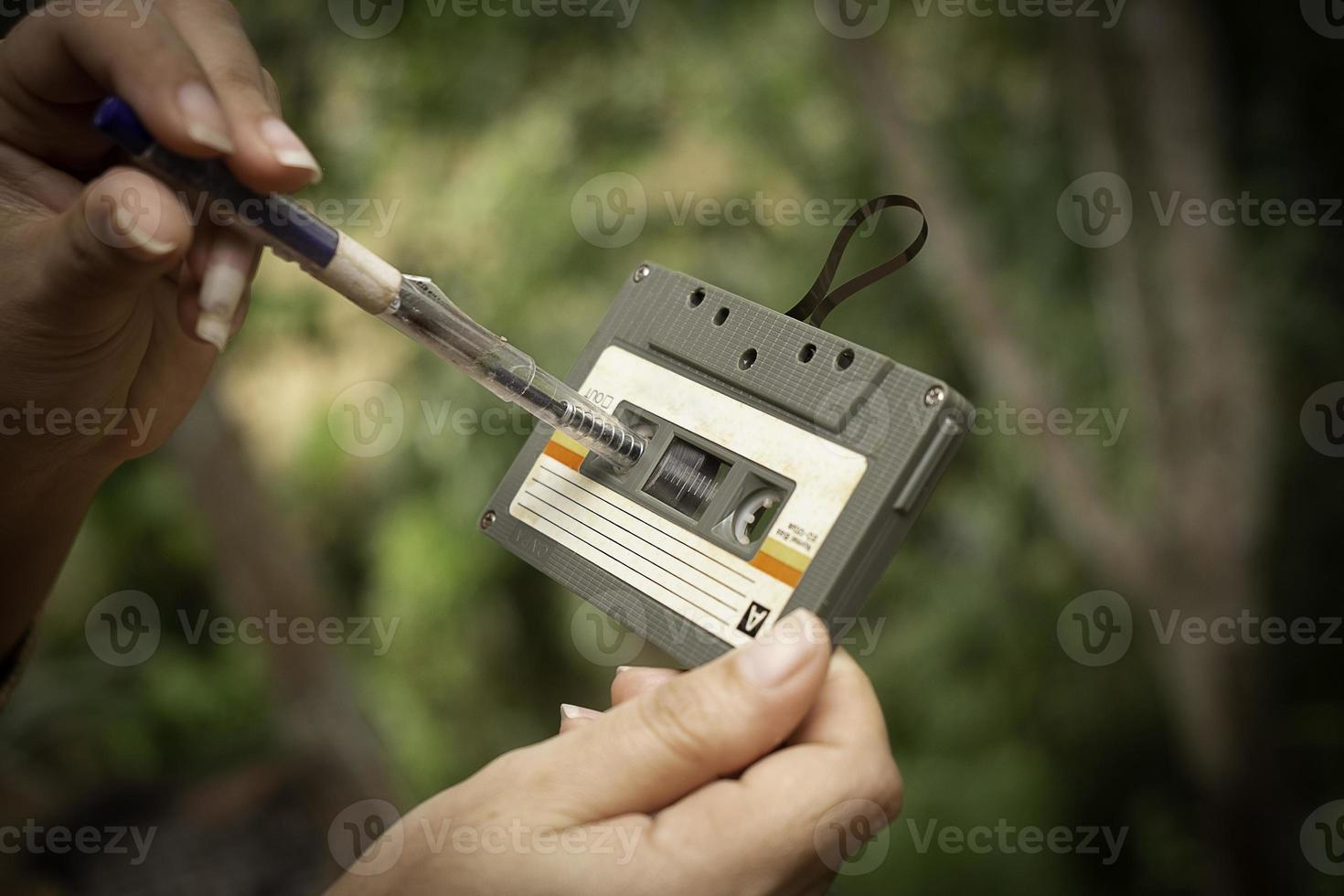 Frauen spulen eine Kassette Vintage-Kompaktkassette auf unscharfem Hintergrund zurück, Nahaufnahme von alten Tonbändern, ret foto