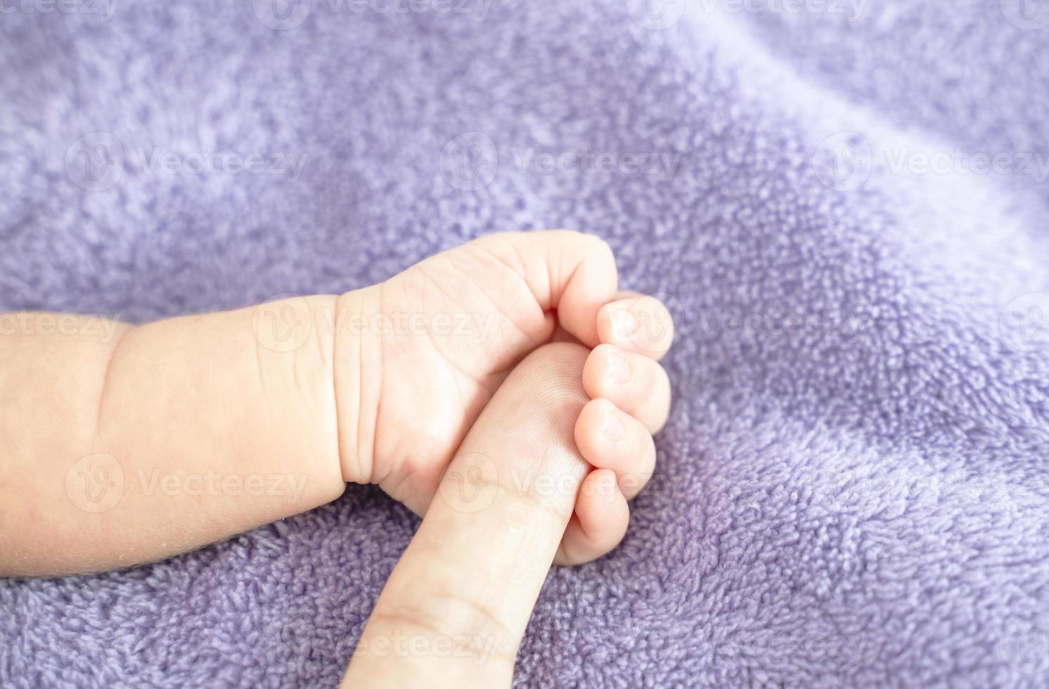 Nahaufnahme, Babyhand hält den Finger eines Elternteils, symbolisch für Liebe, Schutz für ein Neugeborenes. foto