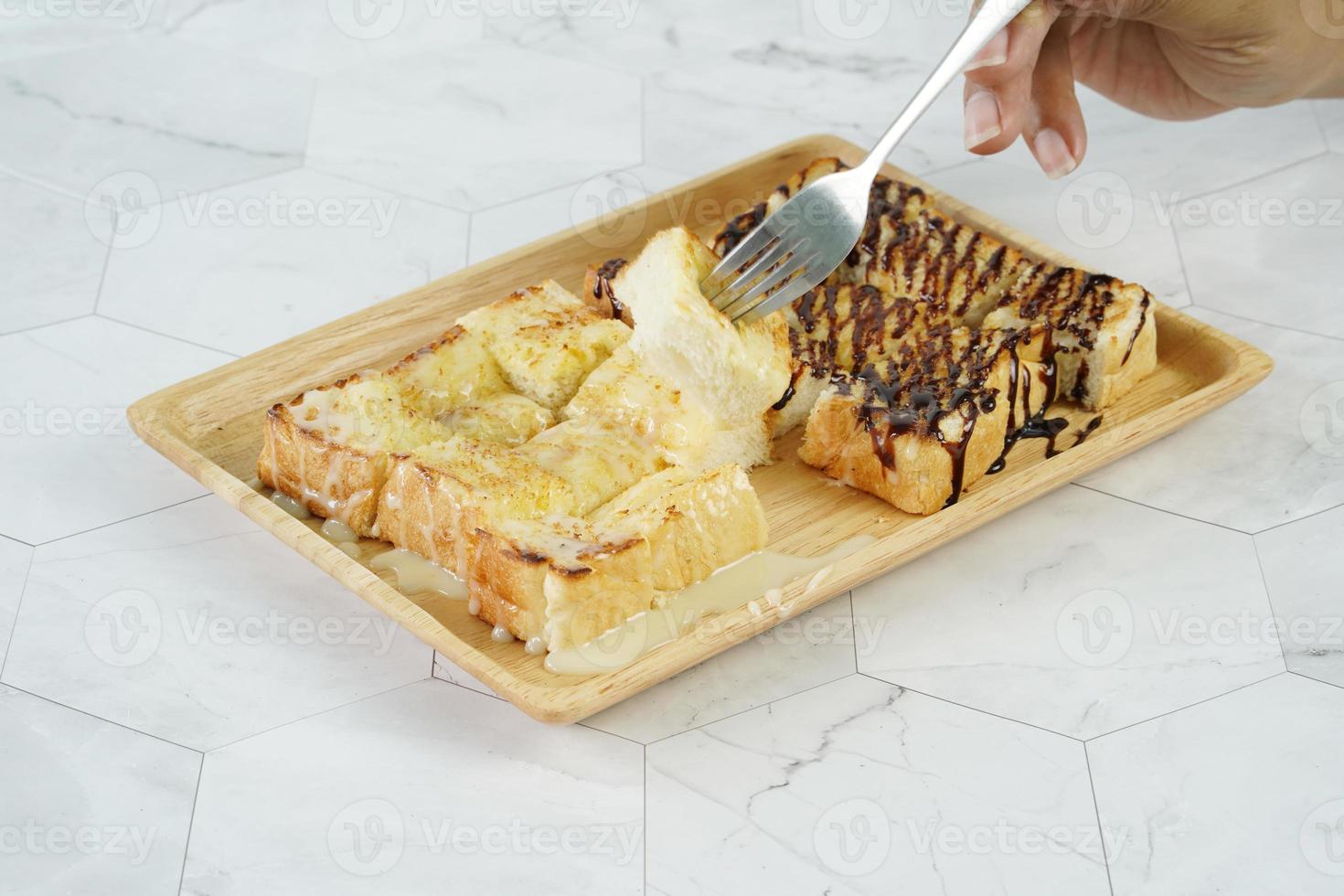 Toast mit gesüßter Kondensmilch und Schokoladensirup auf Holzplatte. foto