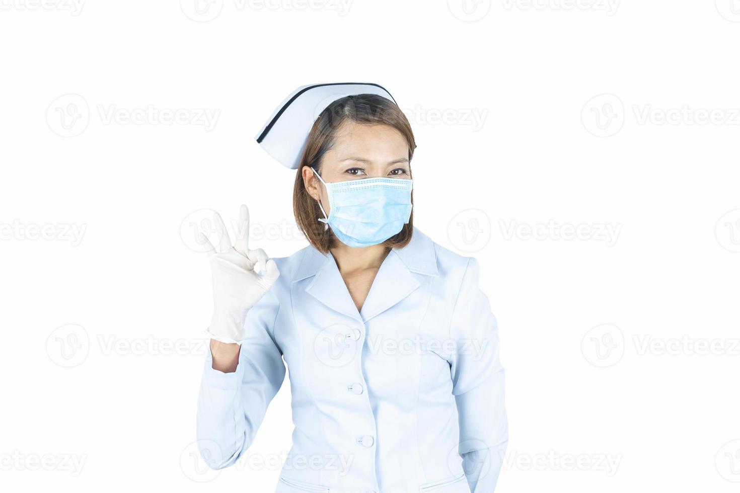 Krankenschwester in weißem medizinischem Kittel, sterile Gesichtsmaske mit ok Geste. foto