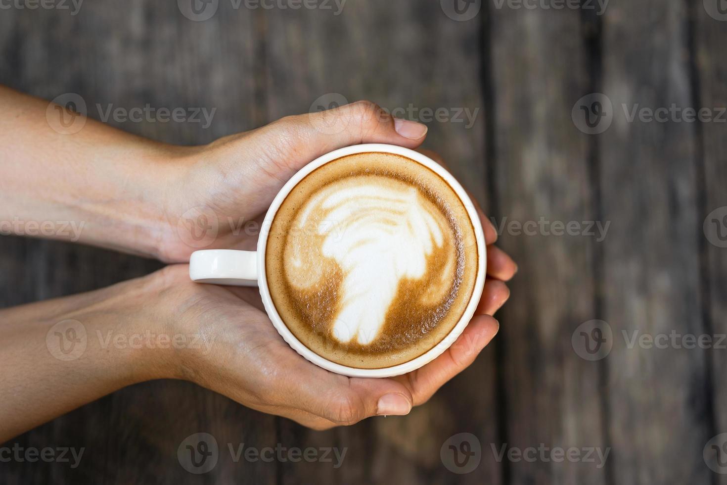 weibliche Hände, die eine Tasse Kaffee auf Holztischhintergrund halten foto