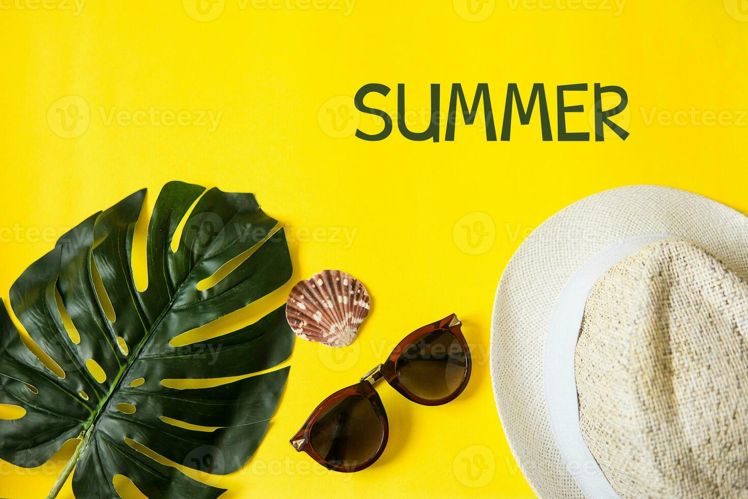 Strand Zubehör auf das Gelb Hintergrund - - Sonnenbrille und gestreift Hut. Sommer- ist Kommen Konzept.tropisch Blätter Monstera. Sommer- eben legen, oben Sicht. Text Sommer. foto