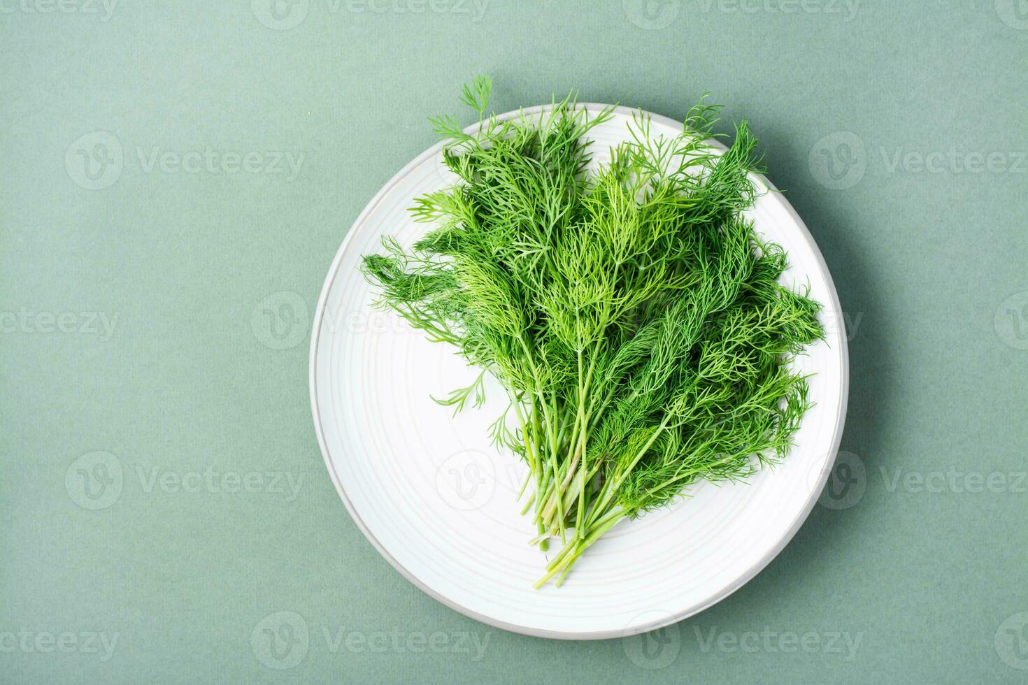 ein Bündel von frisch Dill auf ein Teller auf ein Grün Hintergrund. Vitamin Grüns im ein gesund Diät. oben Aussicht foto