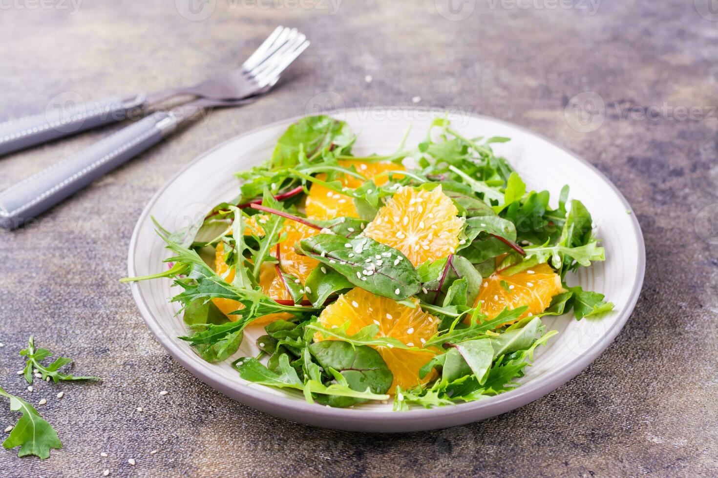 Diät Vegetarier Vitamin Salat von Orange Stücke und mischen von Rucola, Mangold und mizun Blätter auf ein Teller auf das Tabelle foto