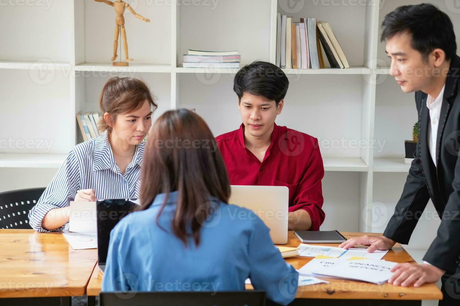 Das asiatische Geschäftsteam besteht aus Marketingmitarbeitern. Buchhalter und Finanzreferent helfen sich gegenseitig bei der Analyse von Unternehmensgewinnen mithilfe von Tablets. Taschenrechner-Laptops, Millimeterpapier und Firmenkugelschreiber. foto