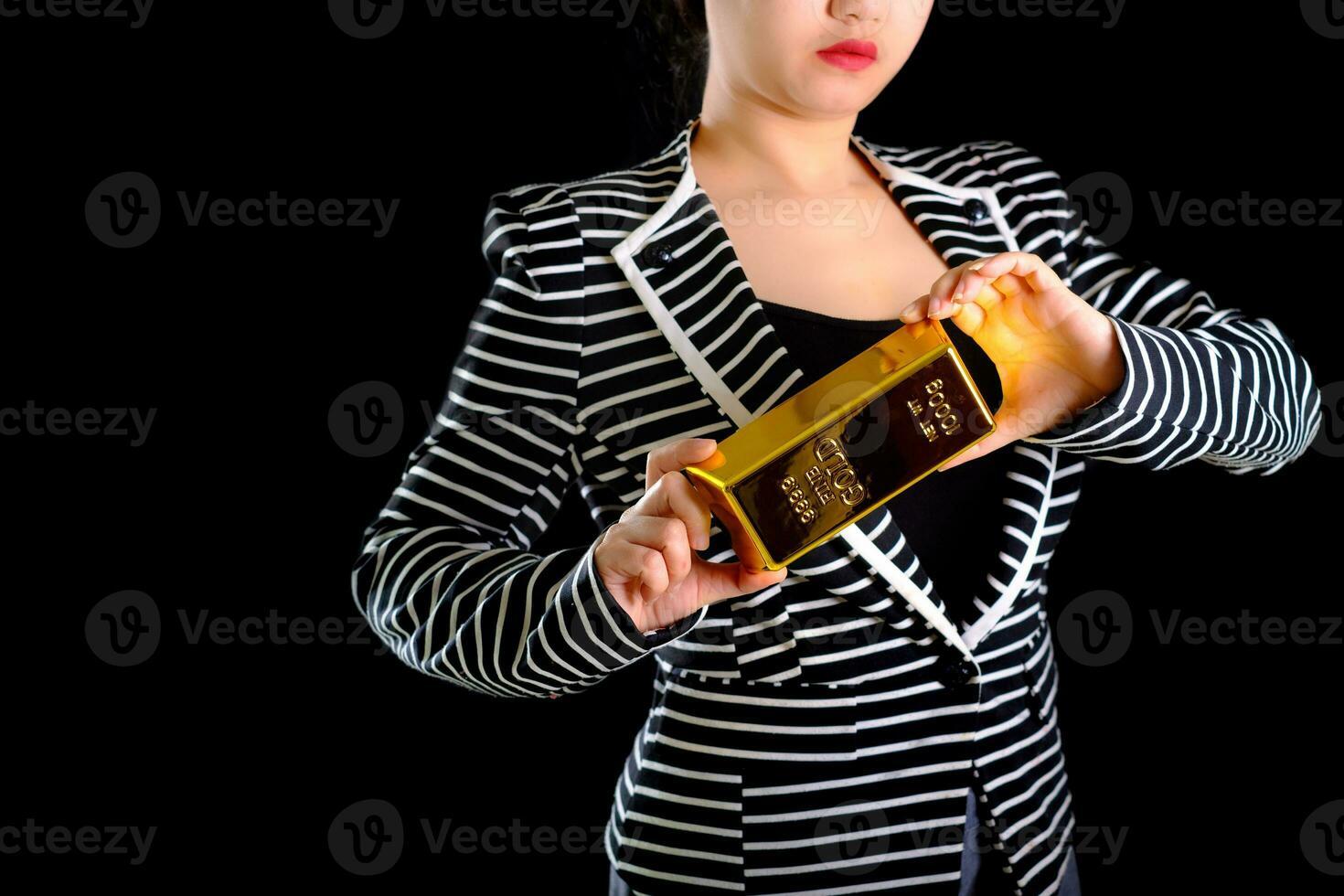 Geschäftsfrau, die den Goldbarren auf schwarzem Hintergrund hält foto