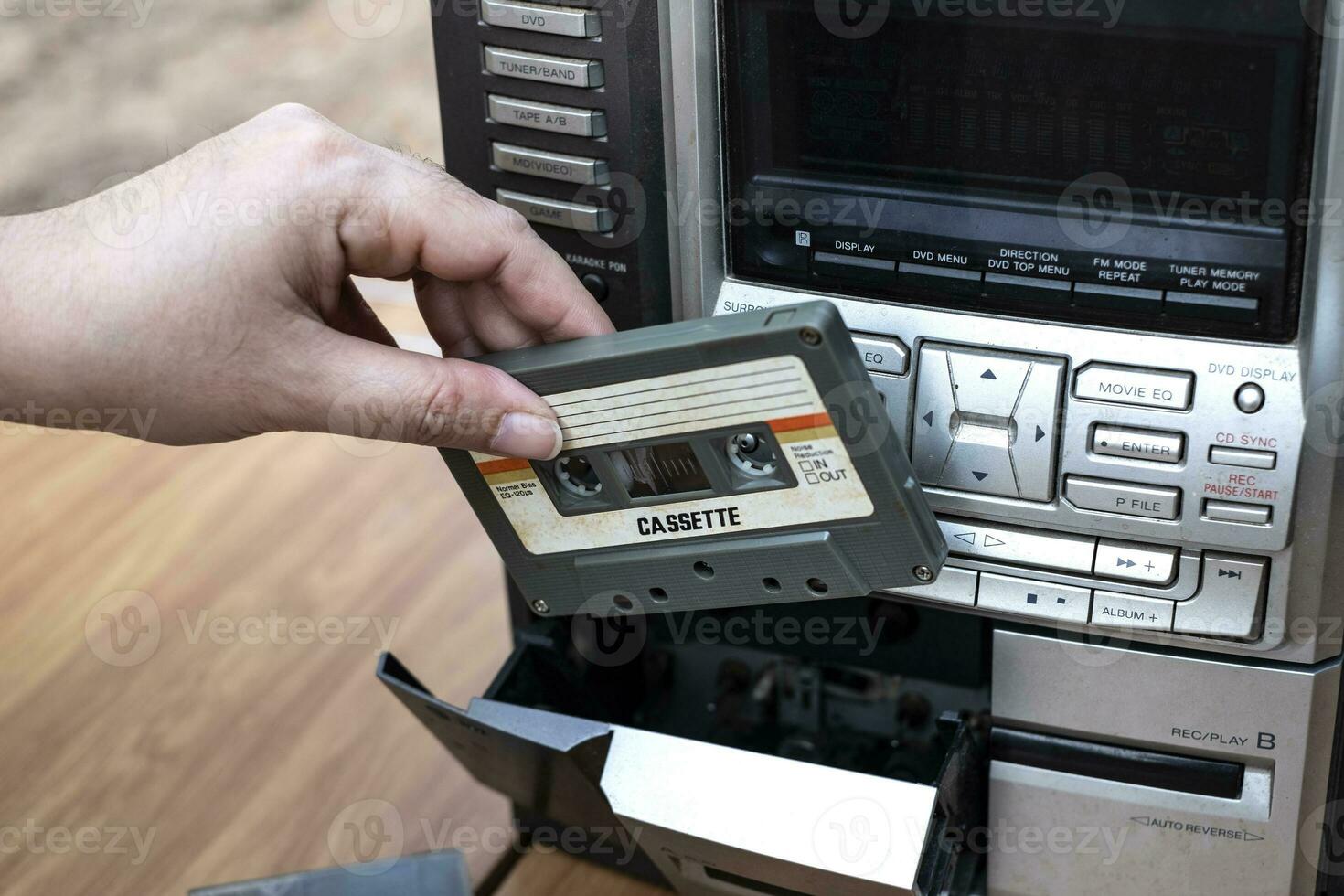 Frauen Hand, die Kassette in altmodischen Audio-Kassettenspieler auf Holzhintergrund des oberen Schreibtisches einlegt foto