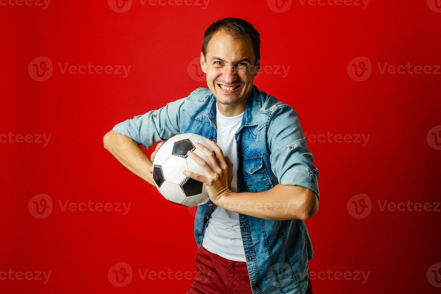 gut aussehend Mann halten ein Fußball Ball Über rot Backgound foto