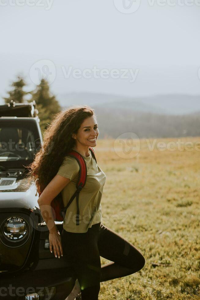 junge frau, die sich auf einer geländefahrzeughaube auf dem land entspannt foto