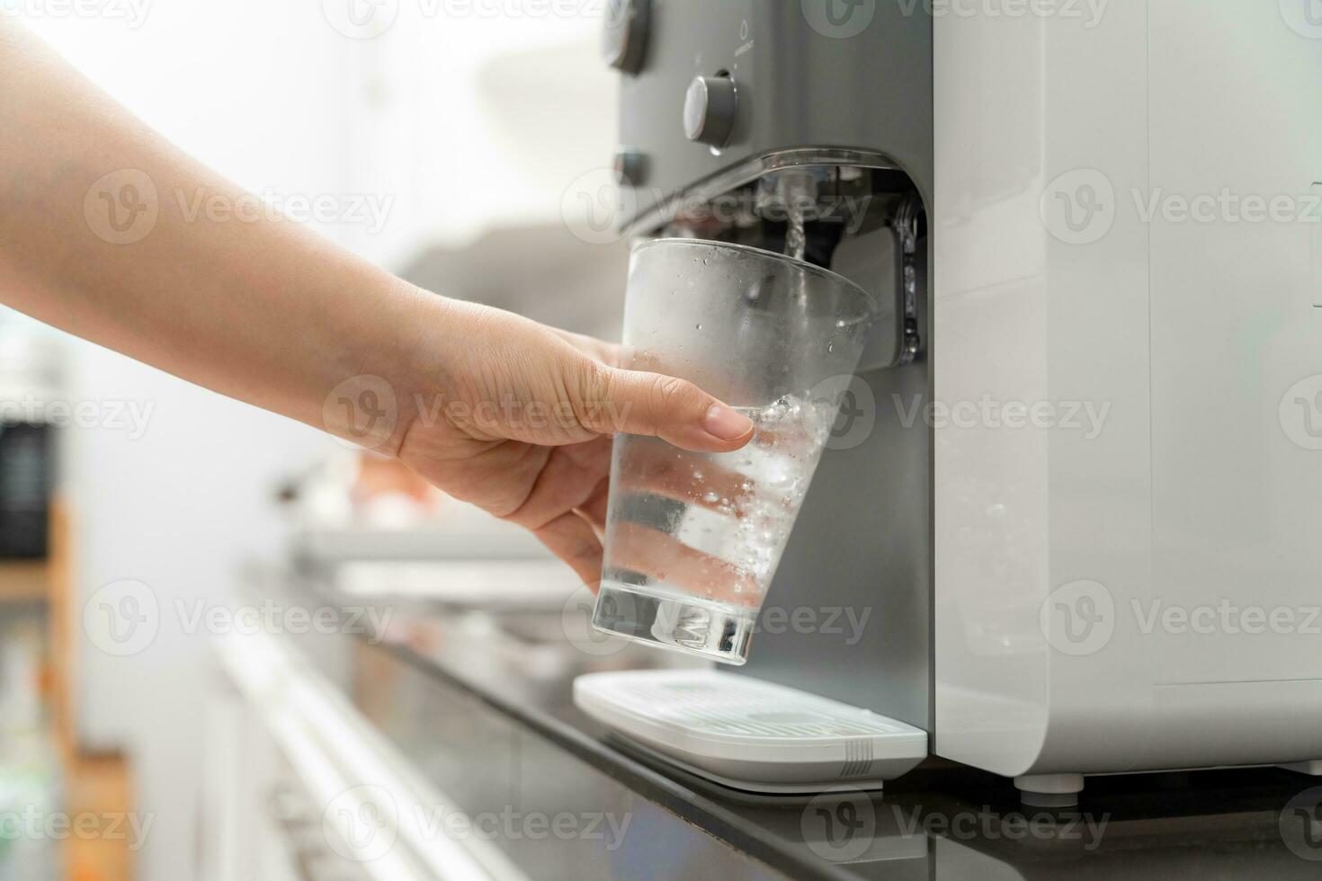 Nahansicht Hand von Frau Trinken Wasser ist gegossen von Wasser Kühler in das Glas, Trinken Wasser Maschine foto