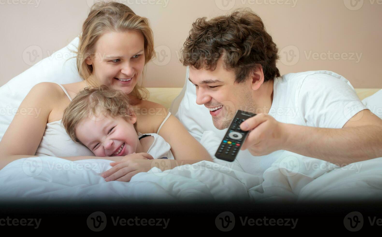 glücklich Familie Lügen im Bett Aufpassen Fernsehen foto