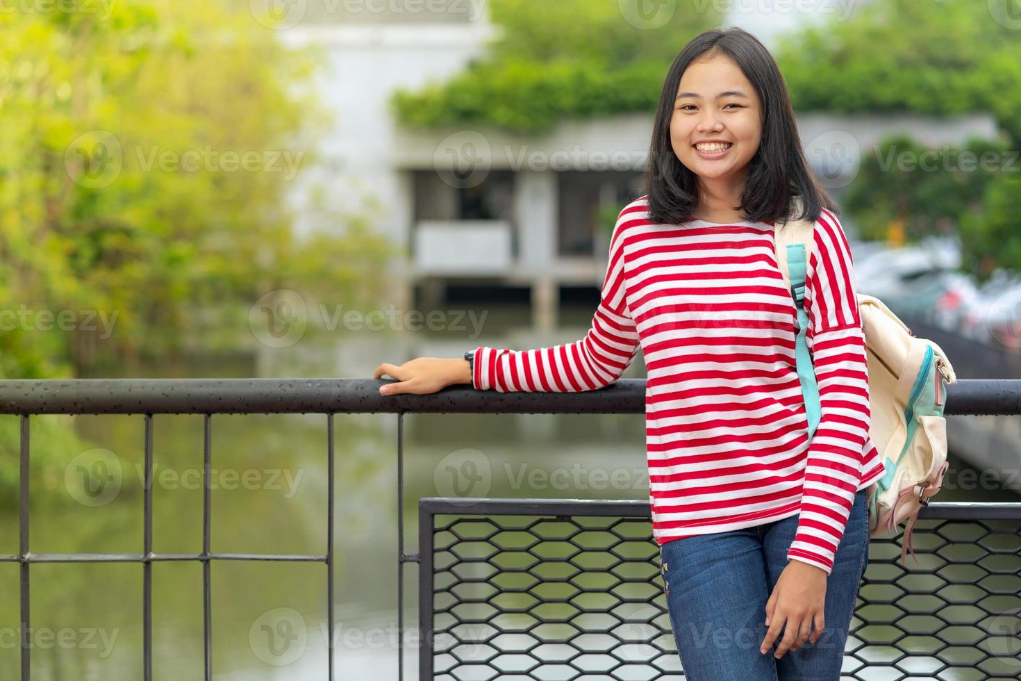 asiatisches studentenmädchen, das an einem sonnigen sommertag im park steht foto