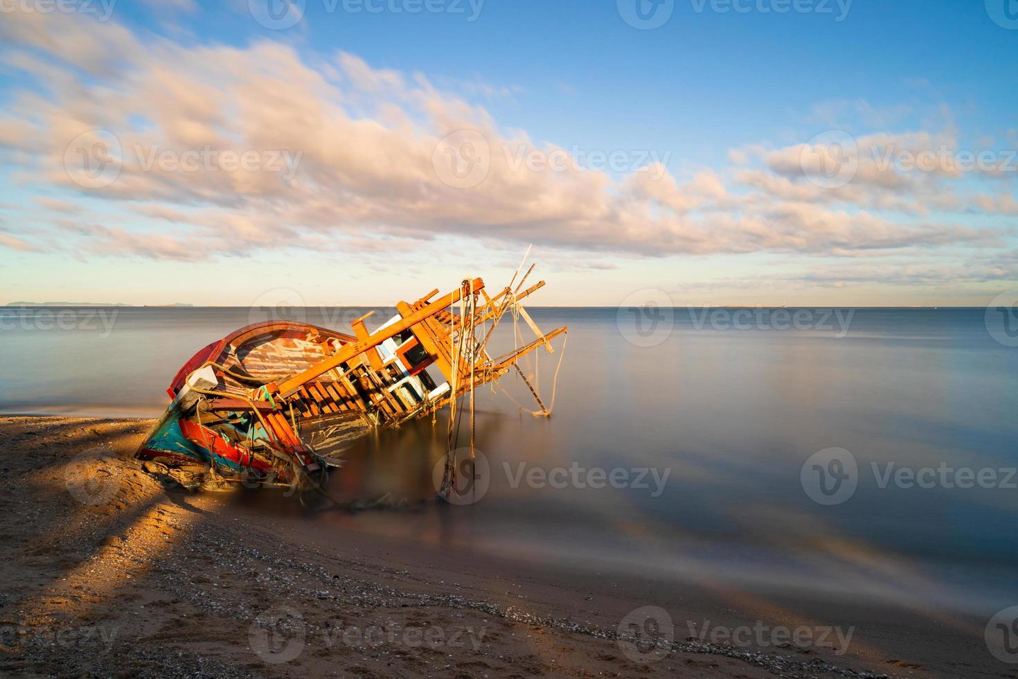 beschädigtes Fischerboot am Strand bei Sonnenaufgang foto