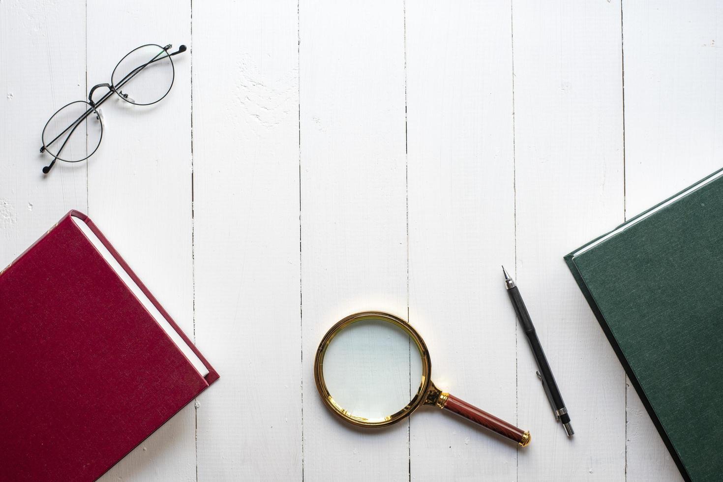 Bildungskonzept, Buch, Stift, Brille, Lupe auf weißem Holzhintergrund foto
