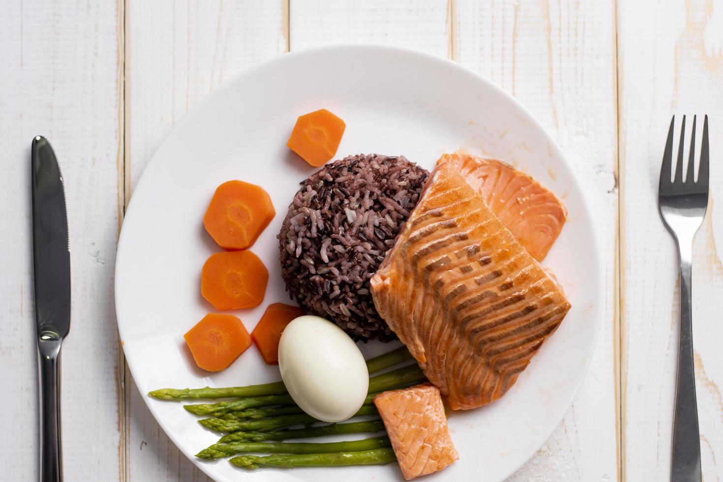 Gesundheitskonzept, Lachs mit Reis und Gemüse auf Holzhintergrund foto