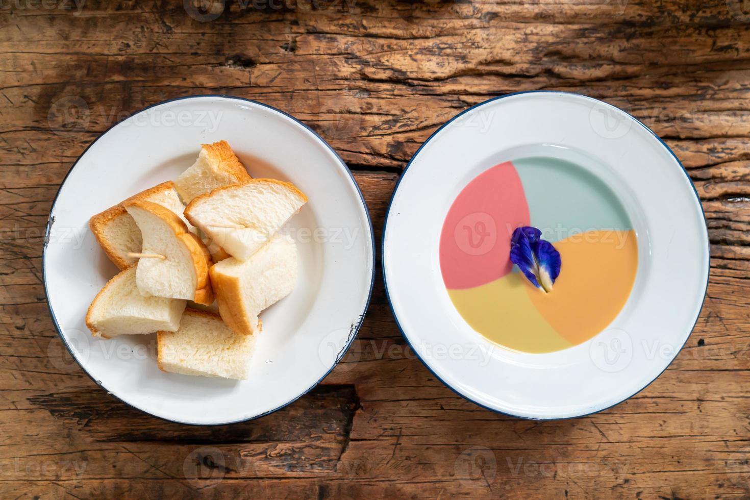 gedämpftes Toastbrot mit buntem Vanillepudding auf Holzhintergrund foto