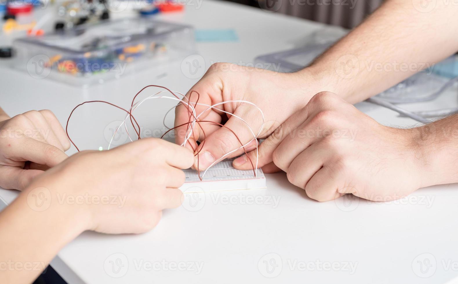 Junge, der mit LED-Leuchten auf Experimentiertafel für Wissenschaftsprojekt arbeitet foto