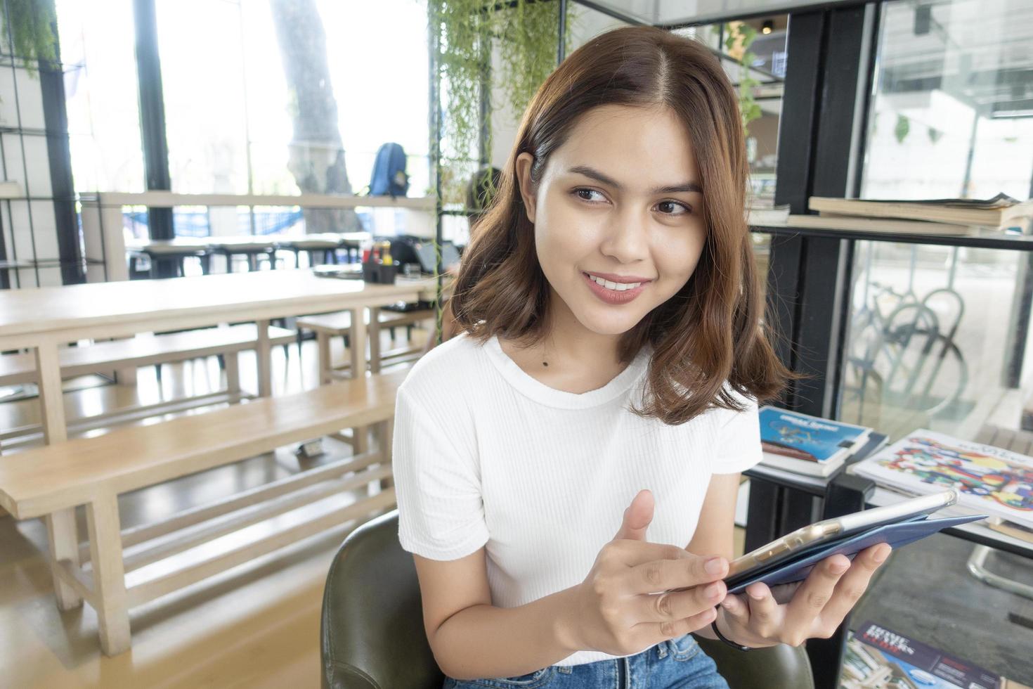 Schönes Geschäftsmädchen, das mit Tablet, Smartphone arbeitet und Kaffee im Café trinkt? foto