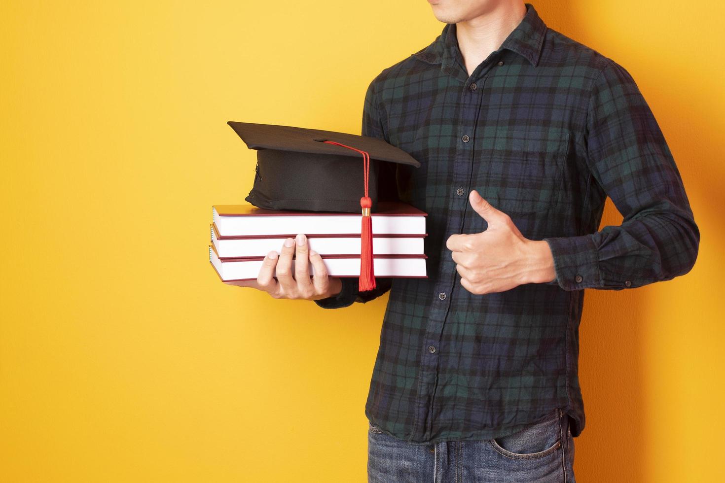 Universitätsmann ist glücklich mit Abschluss auf gelbem Hintergrund foto