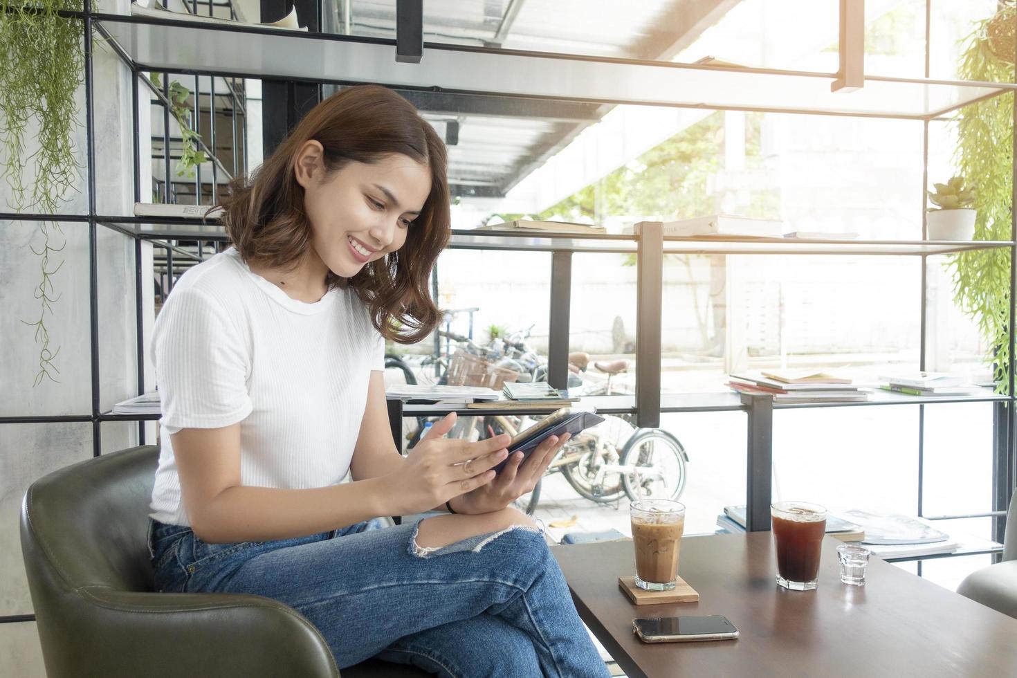 Schönes Geschäftsmädchen, das mit Tablet, Smartphone arbeitet und Kaffee im Café trinkt? foto