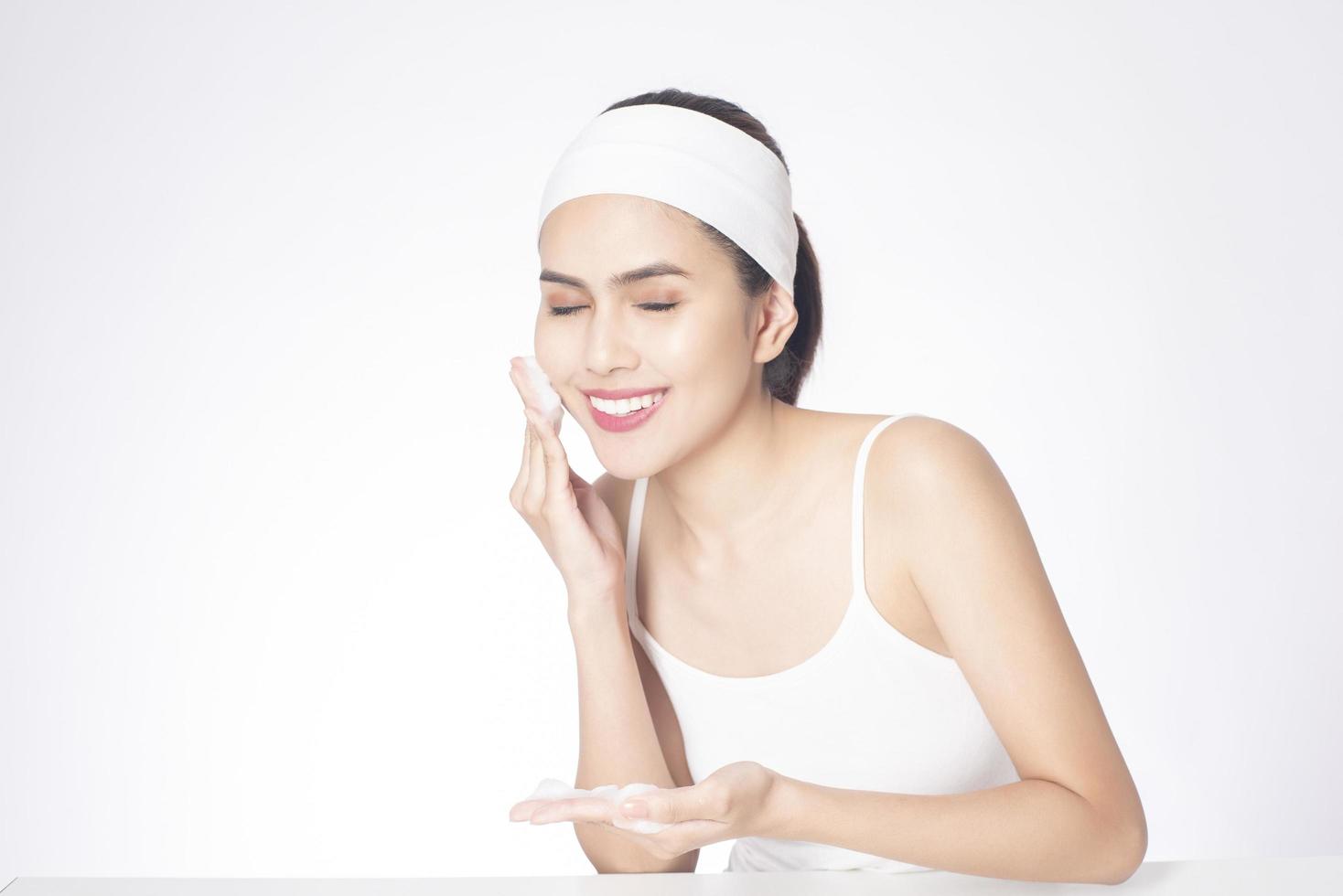 schöne Frau wäscht ihr Gesicht auf weißem Hintergrund foto