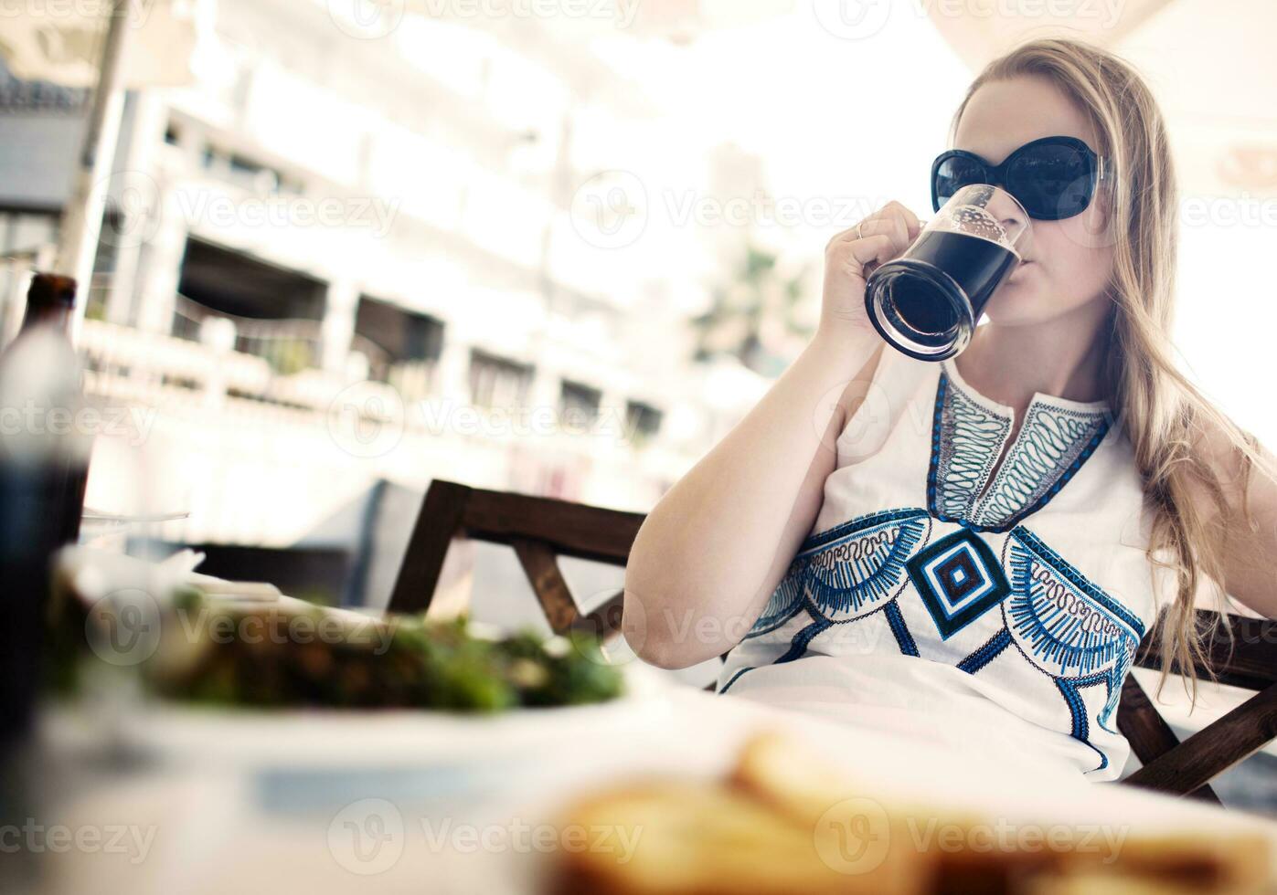 Frau genießt ein dunkles Bier mit ihrer Mahlzeit foto