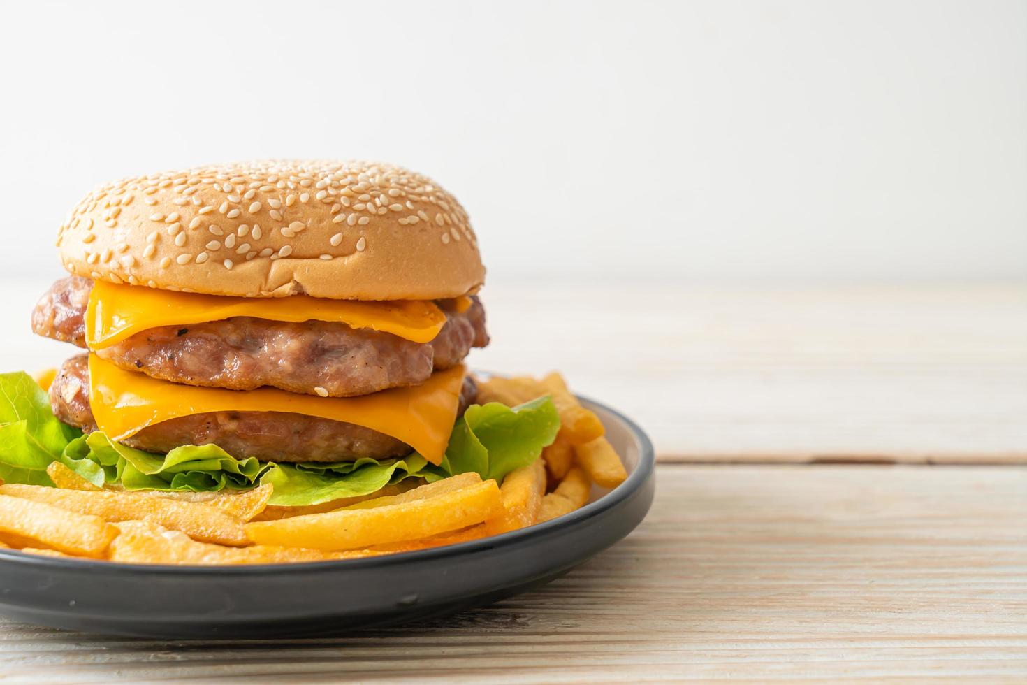 Schweinefleisch-Hamburger oder Schweinefleisch-Burger mit Käse und Pommes frites foto