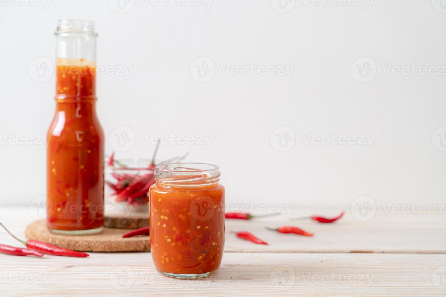 Chili oder Chilisauce in Flasche und Glas auf Holzhintergrund on foto