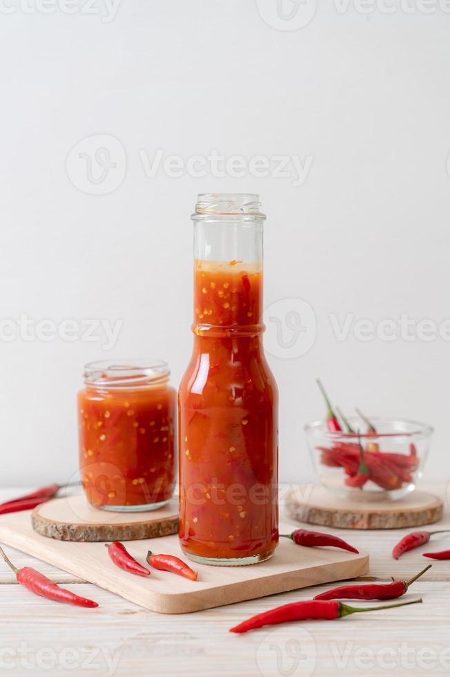 Chili oder Chilisauce in Flasche und Glas auf Holzhintergrund on foto