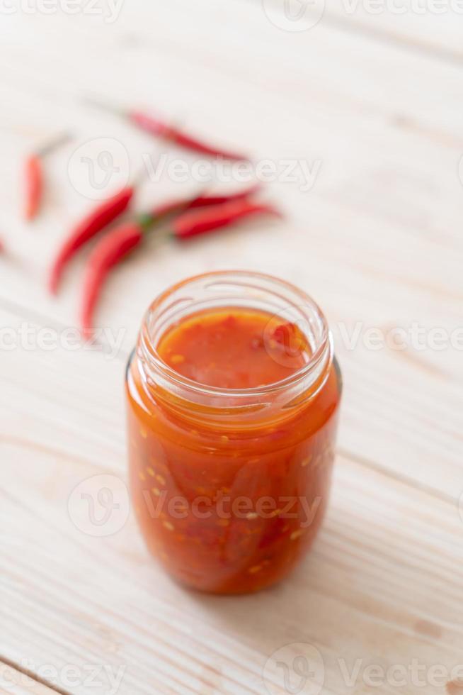 Chili oder Chilisauce in Flasche und Glas auf Holzhintergrund on foto